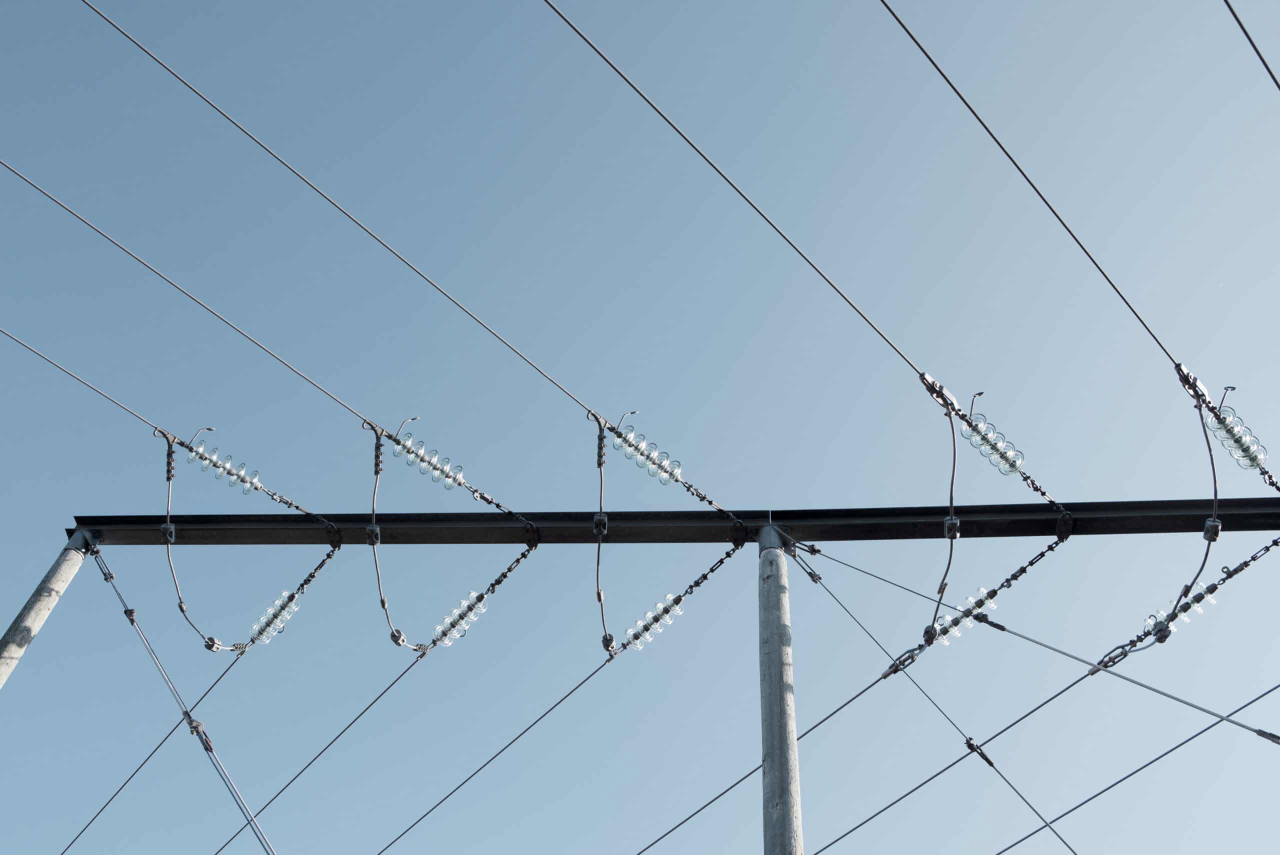 Närbild på stolpar som håller i luftledningar för att symbolisera elnätet.