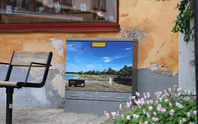 Kabelskåp med sommarmotiv där en person flyger drake.