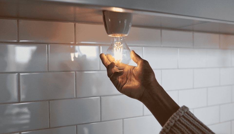 Hand som skruvar i en lampa.