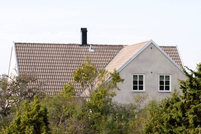 Vit villa bakom buskar och träd.