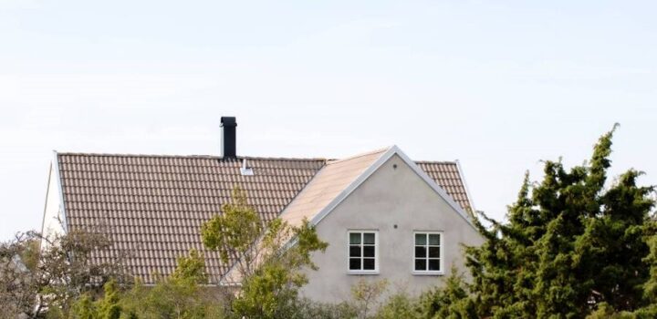 Vit villa bakom buskar och träd.