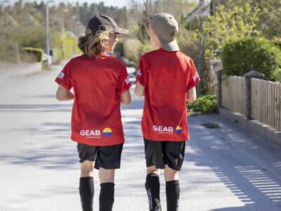 Två killar i fotbollskläder går på en gata