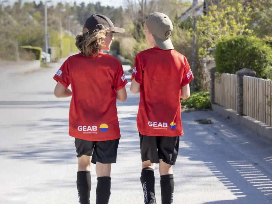 Två killar i fotbollskläder går på en gata